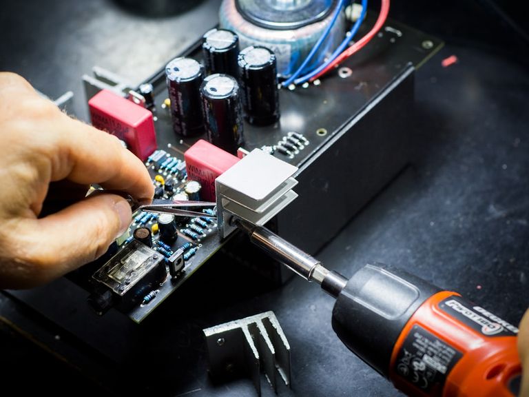 Technician repairing a circuit board with a screwdriver